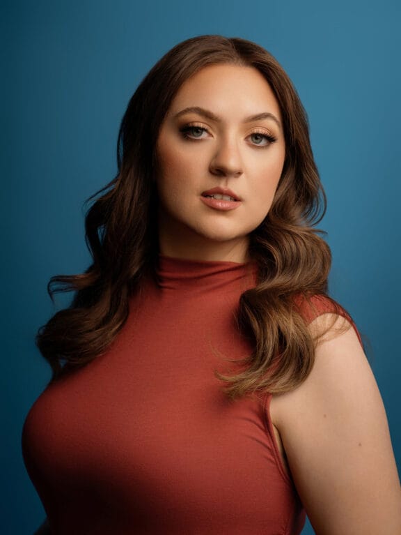 Jorie-actress-actor-headshot-phoenix-az-blue-backdrop-orange-shirt