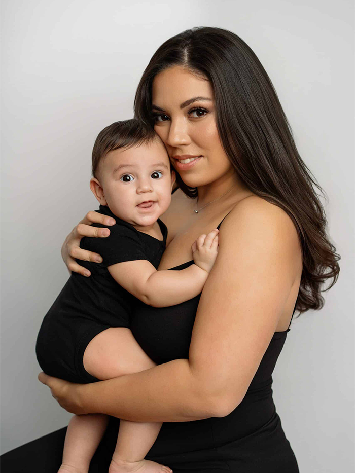 Mother and baby boy in matching black outfits posing together in studio