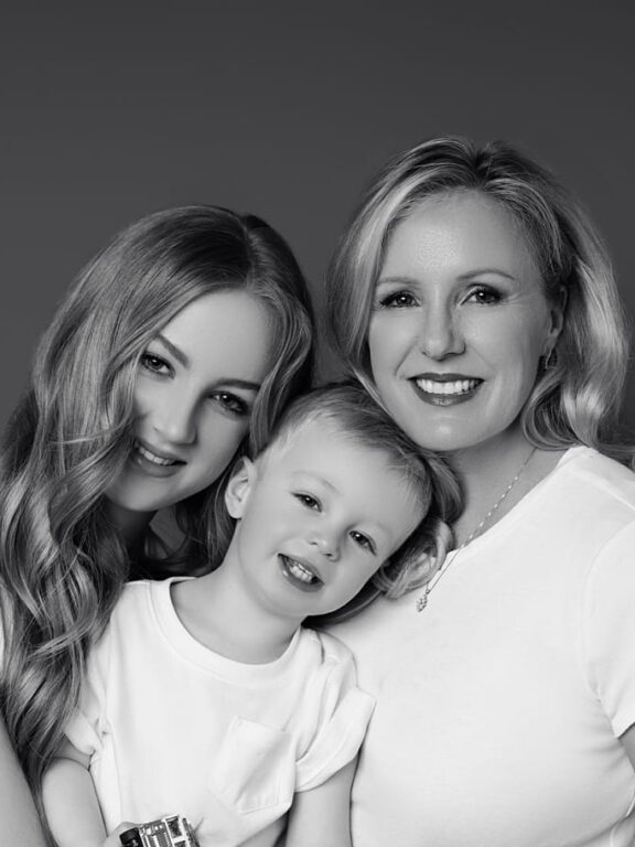 Mother with her daughter and son smiling at the camera at their family session