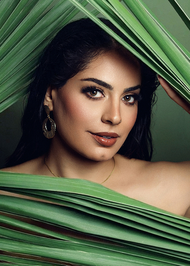 studio session of gorgeous indigenous woman with green palm leaves around her