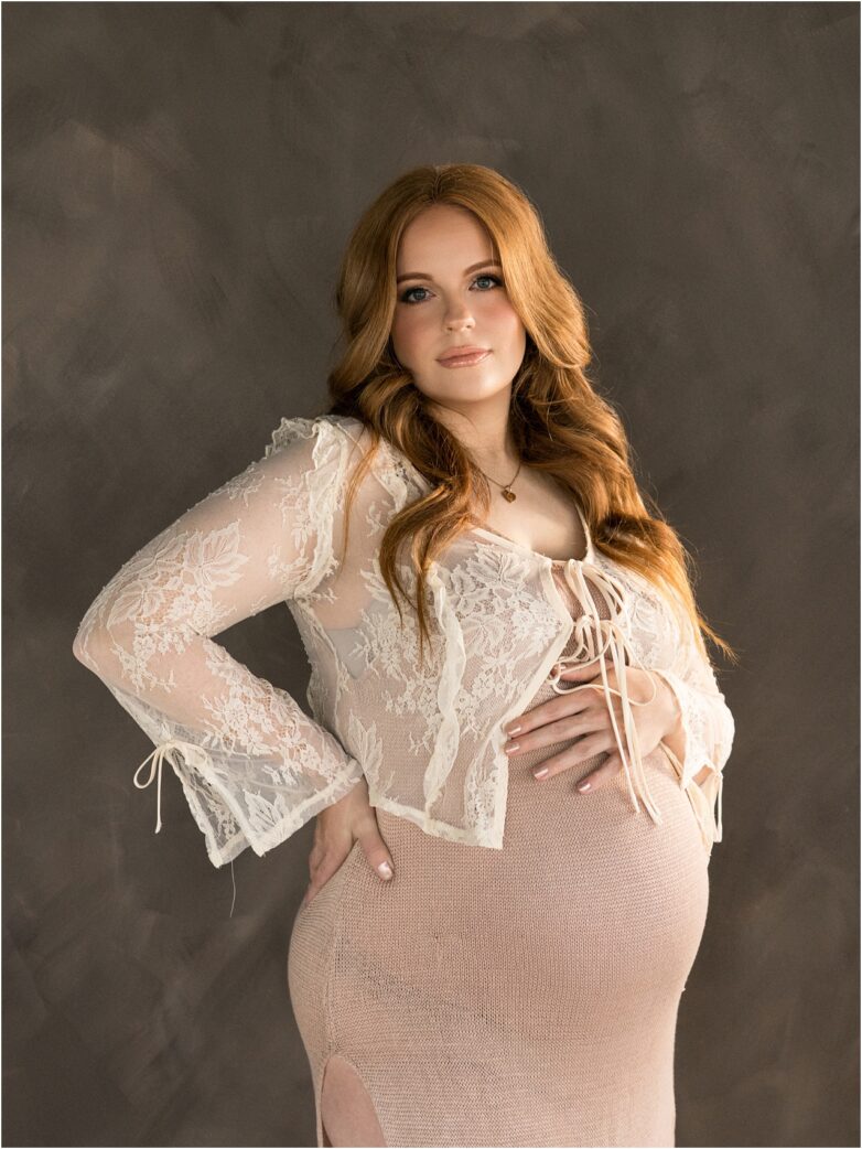 Pregnant woman wearing a lace maternity robe with hands on baby bump